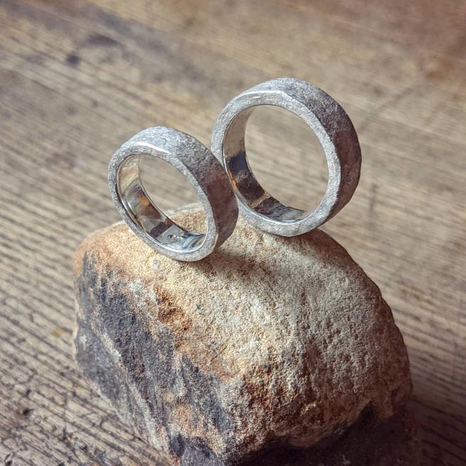 Two silver rings are stood on top of a chunk of gritstone