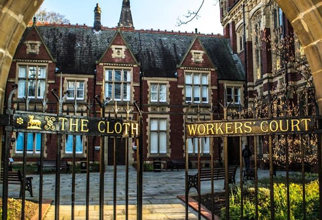 Black and gold gates in front of red brick University buildings