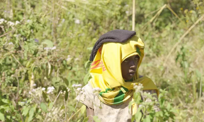 Medium closeup of a woman in walking a field with her head covered by a t-short to protect her from the sun.