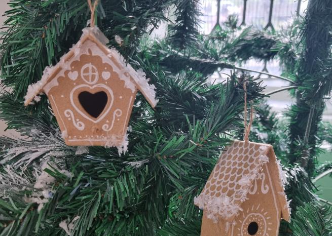 A pair of festive gingerbread houses hanging on a Christmas tree.