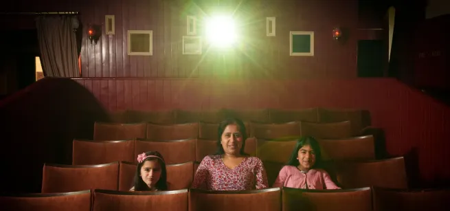 A woman and two girls sat in some cinema seats