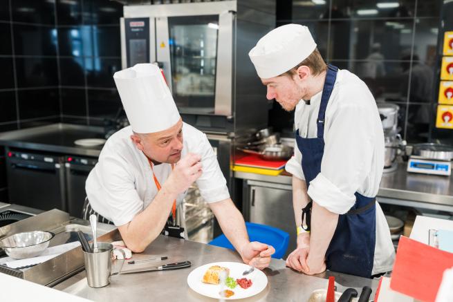 Tutor chef tasting student chefs food in a professional kitchen at Leeds City College.