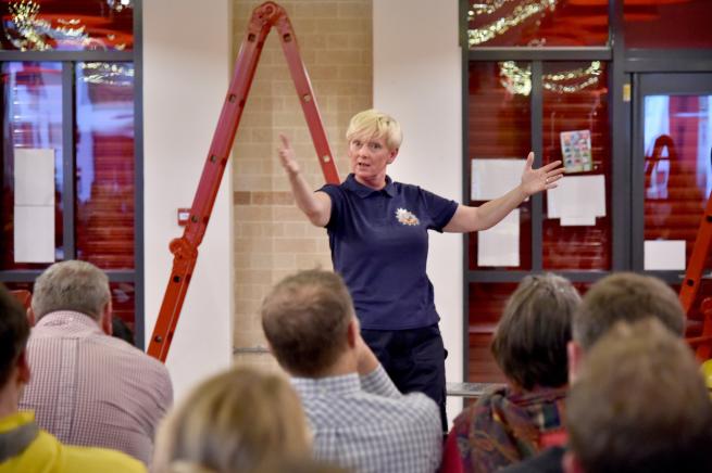 A performer as a women firefighter with her hands out wide. 