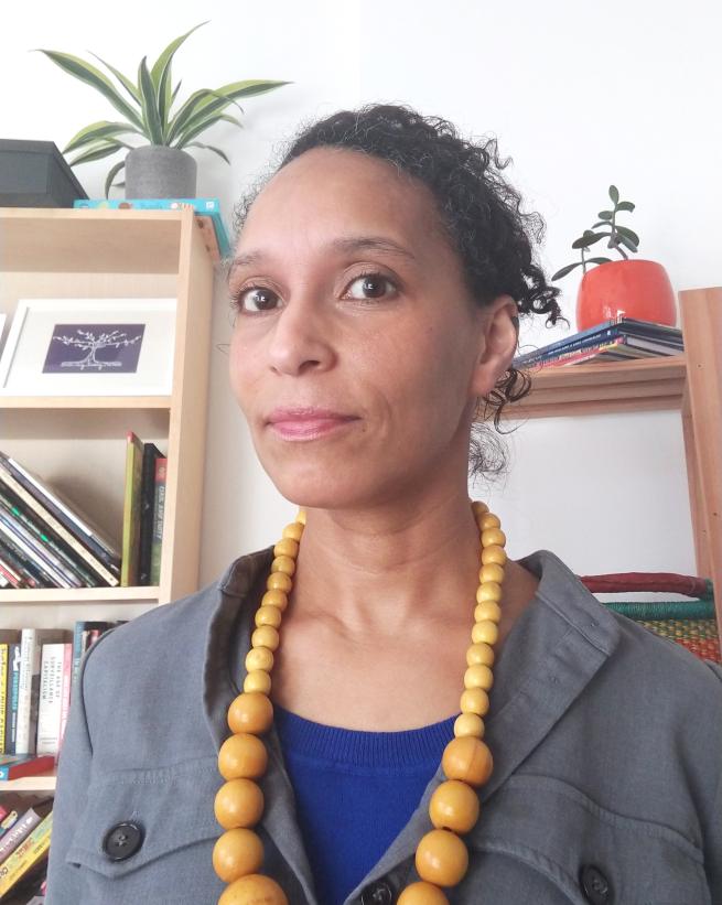 Author/illustrator Lucy Farfort wearing a grey jacket, blue t-shirt and large beads.