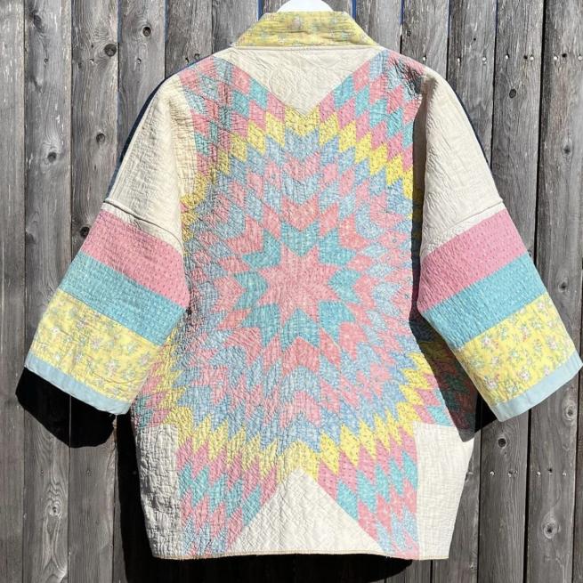 A patchwork jacket in pastel rainbow colours is hung up against a wooden background
