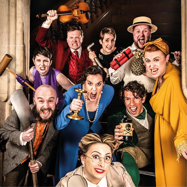 In the stone doorway of a manor house, a group of people in coloured suits and dresses with comically mad expressions each hold a cartoonish weapon towards the camera, including a mallet, dynamite, candlestick and shovel. 