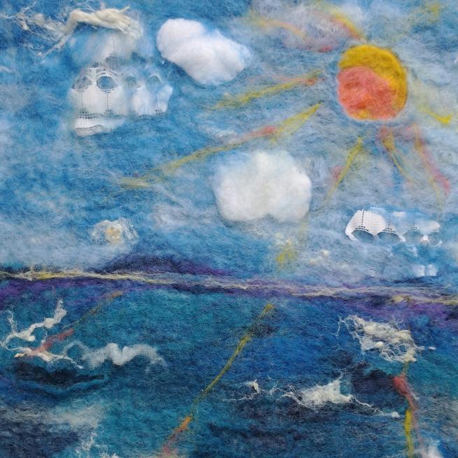 A sun high in a blue sky over a blur ocean, all felted