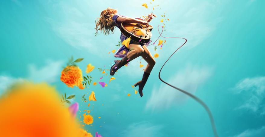 A woman mid jump holding a guitar against a blue sky with clouds