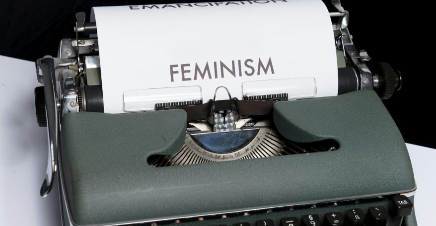 a typewriter with a sheet of paper in it spelling out FEMINISM
