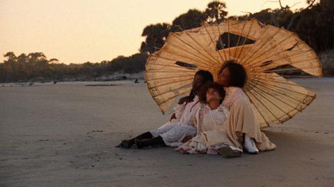 three women under an umbrella on a beach