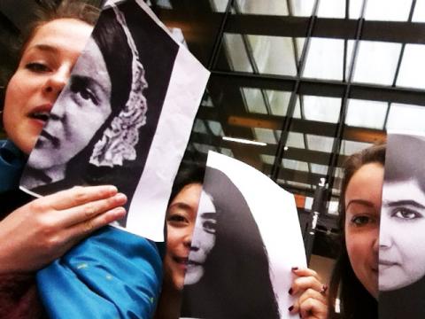 three women holding pictures of faces against their own