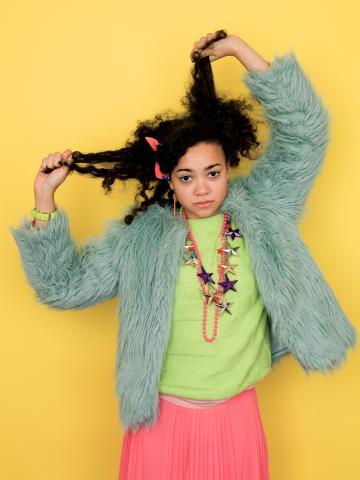 a young woman pulling her own long dark hair in a blue jacket