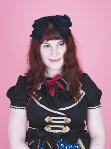 a young woman dressed mainly in black with a hair bow