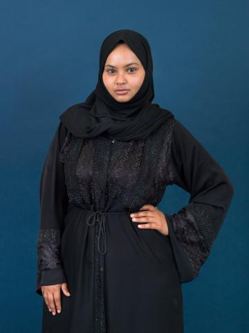 a young woman in headscarf and black clothing striking a pose