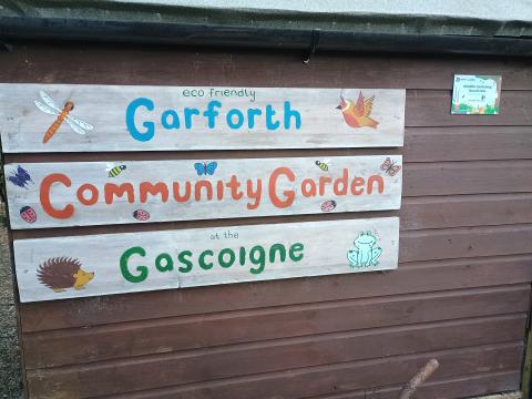A handmade wooden sign saying 'Garforth Community Garden'.