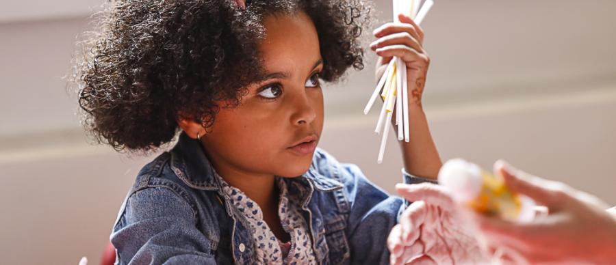 A child holding a handful of craft materials at a table