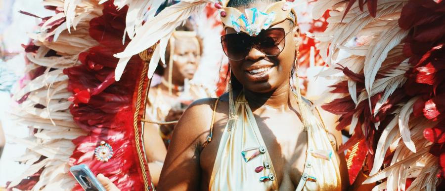 A lady dressed in a gold carnival costume is filming herself on her phone.