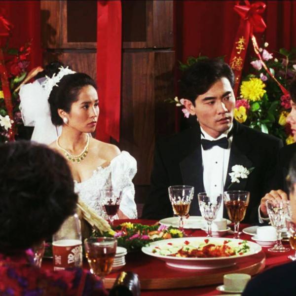 a group of people with bride and groom at a dining table with food and drink