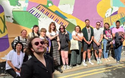 A group of people stand in front of a mural