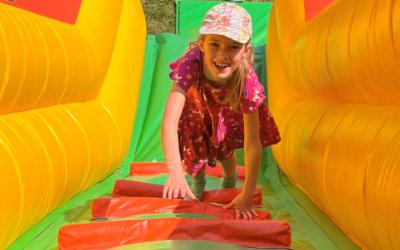 teenage girl climbing up a yellow, green and red inflatable slide