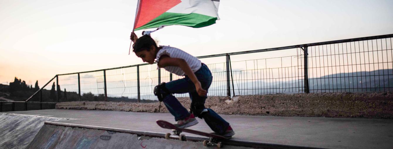 A skateboarder with a Palestinian flag