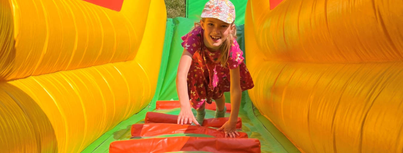 teenage girl climbing up a yellow, green and red inflatable slide